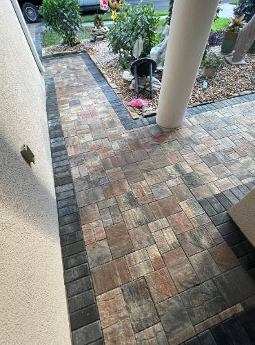 A 200 Square Foot brick paver walkway leading to the front door of a Pasco County home from the driveway. Also seen is a brick paver patio running along the front of the home.