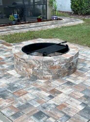 Tan and charcoal fire pit and matching paved backyard patio installed in one day by Suncoast Diamond Pavers.